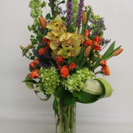 Tall mixed bouquet in a clear glass vase with yellow orchids and orange tulips