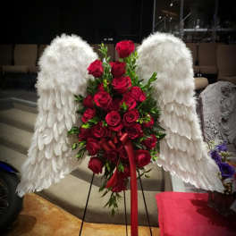 Red rose arrangement with white angel wings on a stand