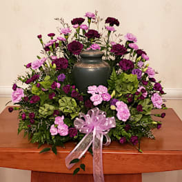 Purple and pink carnation funeral wreath with a dark urn centerpiece