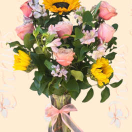 Pink roses and yellow sunflowers in a glass vase with a ribbon