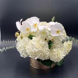 White orchids and hydrangeas in a low woven basket