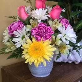 Bouquet of pink roses, daisies, and carnations in a white vase
