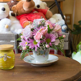 Pink and lavender bouquet in a floral teacup on a saucer