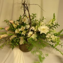 White floral arrangement with calla lilies and daisies in a brown vase