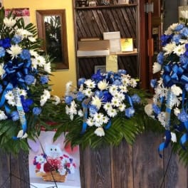 Three blue-and-white floral wreaths with ribbons on stands