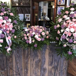 Three pink and purple standing floral sprays with ribbon bows