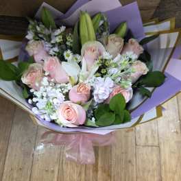 Bouquet of pale pink roses and white lilies with lavender wrapping