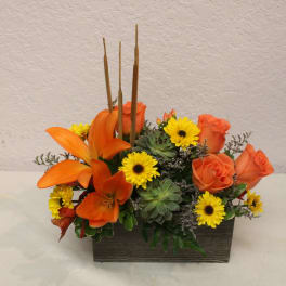 Orange roses and yellow daisies in a rectangular wooden container