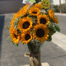Bouquet of sunflowers in a glass vase with a ribbon and emoji pick