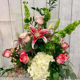 Tall floral arrangement with pink lilies, roses, and white hydrangea in a vase