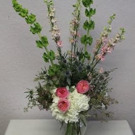 Tall floral arrangement with pink and white blooms in a glass vase