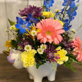 Colorful bouquet in a white unicorn planter with pink, blue, yellow, and purple flowers