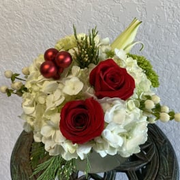 Red roses and white hydrangeas in a low arrangement with red ornaments