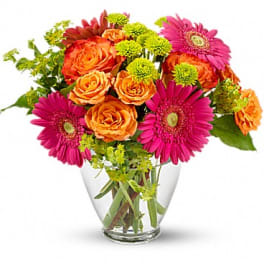Bouquet of orange roses and pink gerbera daisies in a clear glass vase