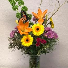 Colorful mixed bouquet in a glass vase with orange lilies and yellow daisies
