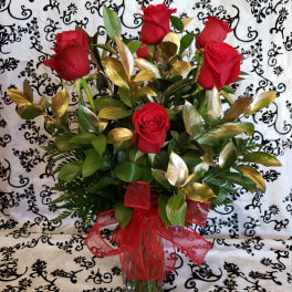Red roses arranged in a clear glass vase with a red ribbon