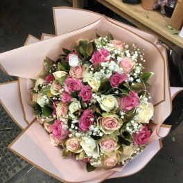 Bouquet of pink, cream, and white roses wrapped in blush paper