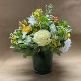 Mixed bouquet of white, yellow, and peach flowers in a dark green vase