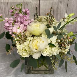 White and pale pink floral arrangement in a square glass vase