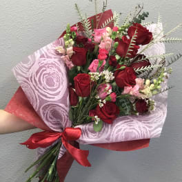 Bouquet of red and pink roses wrapped in patterned paper with a red ribbon