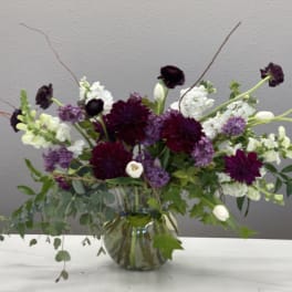 Purple and white floral arrangement in a glass vase