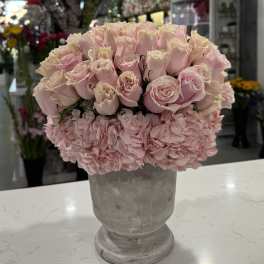 Pink roses and hydrangeas arranged in a gray pedestal vase