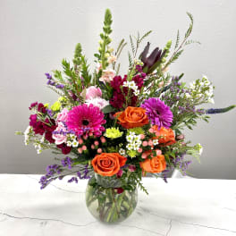 Mixed bouquet of orange and pink flowers in a glass vase