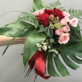Bouquet of red and pink roses with large tropical leaves