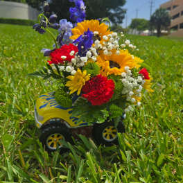 Bright mixed bouquet in a decorated toy truck on grass