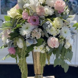 Large pastel floral arrangement in a tall urn vase
