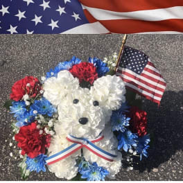 White teddy bear made of flowers with red and blue blooms and a small U.S. flag