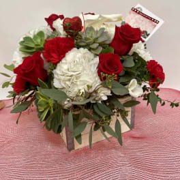 Red roses and white flowers in a wooden box with succulents