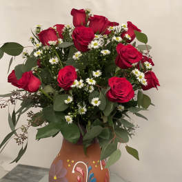 Bouquet of red roses and white daisies in a painted vase