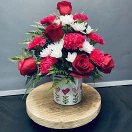Red roses and pink carnations with white daisies in a heart-patterned vase