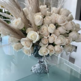 Cream rose bouquet with tall pampas grass in a glass vase