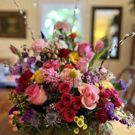 Colorful mixed flower arrangement in a wooden box with tall pussy willow stems