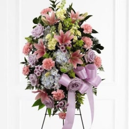 Standing floral spray with pink lilies, lavender roses, and a purple ribbon