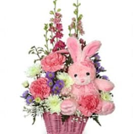 Pink bunny plush in a basket with mixed flowers