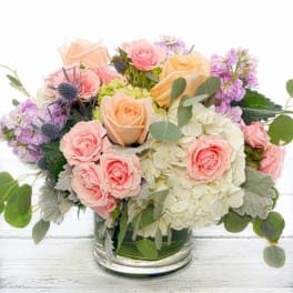Pastel roses and hydrangeas arranged in a clear glass vase