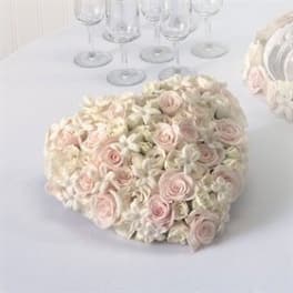 Heart-shaped bouquet of pale pink and white roses on a white table