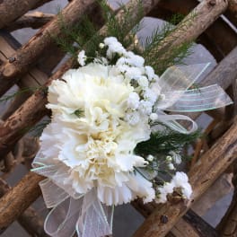White carnation corsage with ribbon and greenery