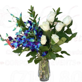 White roses and blue orchids in a clear glass vase