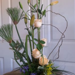 Tall floral arrangement with cream roses and lilies in a white vase