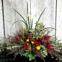 Large mixed floral arrangement with red and yellow blooms and tall greenery