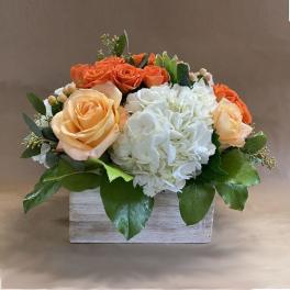 Orange and white roses with white hydrangea in a wooden box