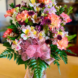 Mixed pink and white bouquet in a glass vase with a pink ribbon