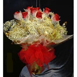 Bouquet of red roses wrapped in white mesh with a red bow