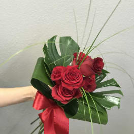 Red rose bouquet with tropical leaves and a red ribbon
