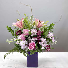 Pink lilies and roses in a purple vase