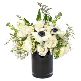White roses and anemones arranged in a black vase